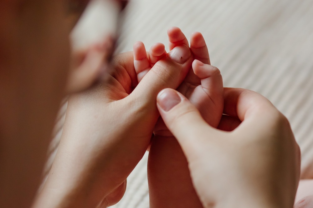 Zeigt Babyhand die von einer Mutter mit beiden Händen massiert wird